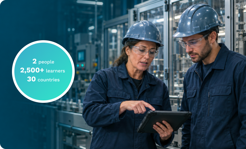 Two manufacturing employees reviewing a tablet. 2 people, 2,500+ learners, 30 countries.